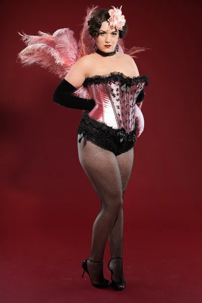 Sexy parodie pin se žena má dlouhé blond vlasy, oblečen v růžové a černé. módní Studio zastřelil izolované na červeném pozadí. — Stock fotografie