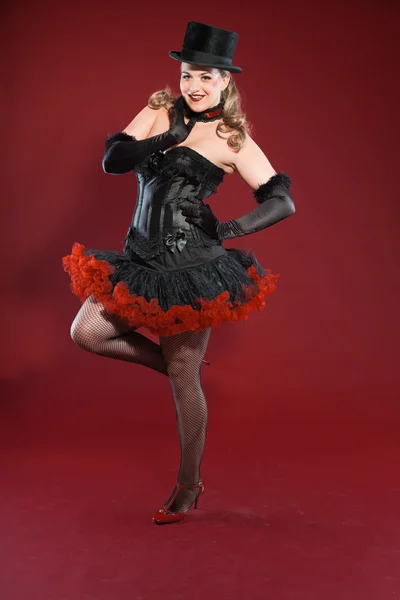 Sexy burlesco pin up mulher com cabelo loiro longo vestido de preto e vermelho. A usar chapéu preto. Estúdio moda tiro isolado no fundo vermelho . — Fotografia de Stock