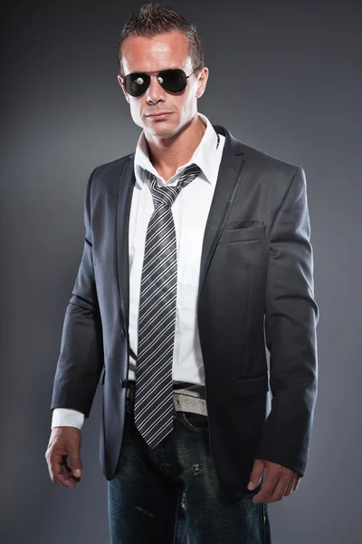 Bello uomo d'affari con occhiali da sole neri e capelli corti biondi. Un tipo tosto. Indossa cravatta e giacca nera . — Foto Stock