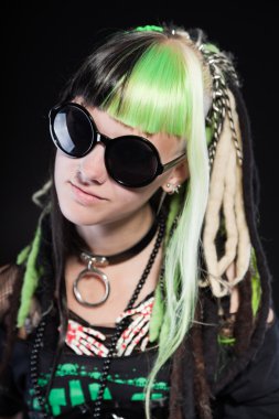 Cyber punk kız yeşil sarı saçları ve siyah arka plan üzerine izole kırmızı gözleri. siyah güneş gözlüğü takıyor. etkileyici bir yüz. Stüdyo vurdu.