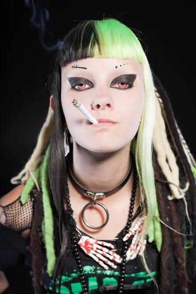 Menina punk cibernético com cabelo loiro verde e olhos vermelhos isolados no fundo preto. Cara expressiva. Fumar um cigarro. Estúdio . — Fotografia de Stock