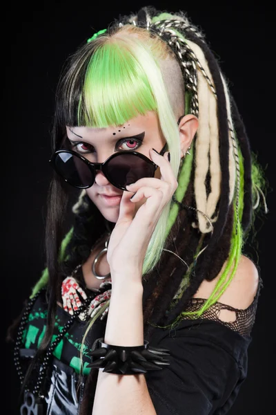 Cyber punk kız yeşil sarı saçları ve siyah arka plan üzerine izole kırmızı gözleri. siyah güneş gözlüğü takıyor. etkileyici bir yüz. Stüdyo vurdu.