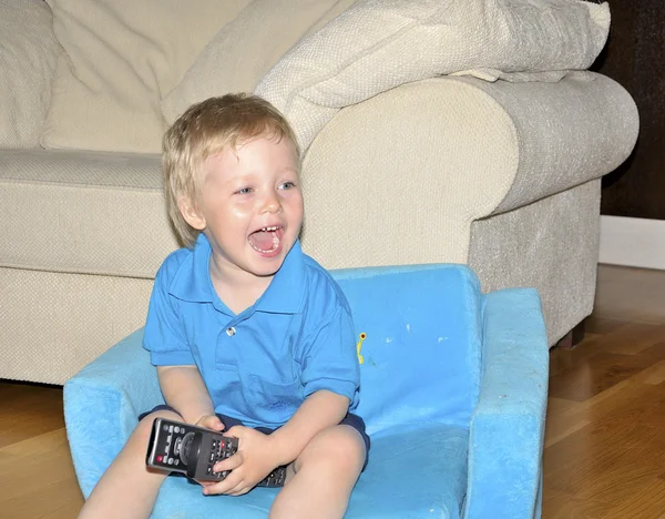 Niedlichen Kind fernsehen, sitzt in einem sehr komfortablen und weichen cha — Stockfoto