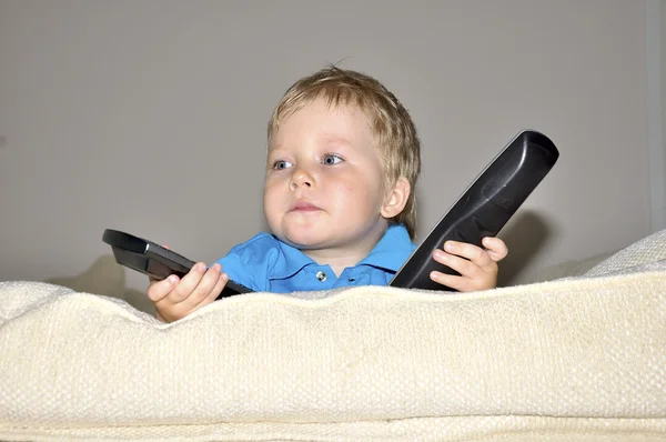 Enfant mignon regardant la télévision, assis dans un cha très confortable et doux — Photo
