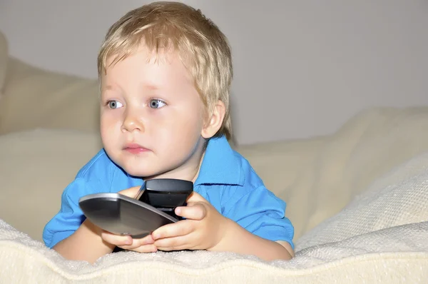Söta unge tittar på tv, sitter i en mycket bekväm och mjuk cha — Stockfoto