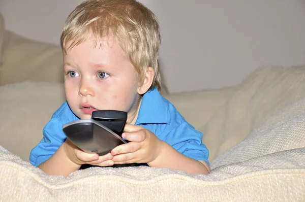 Söta unge tittar på tv, sitter i en mycket bekväm och mjuk cha — Stockfoto