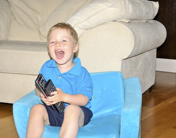 Lindo niño viendo la televisión, sentado en un cha muy cómodo y suave — Foto de Stock