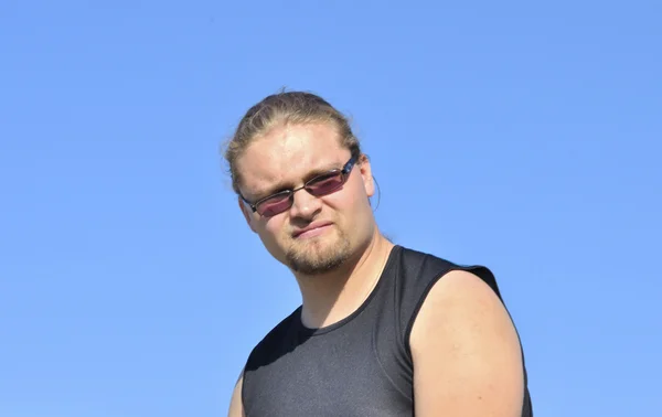 Roztomilý mladý muž s brýlemi na pozadí modré oblohy — Stock fotografie