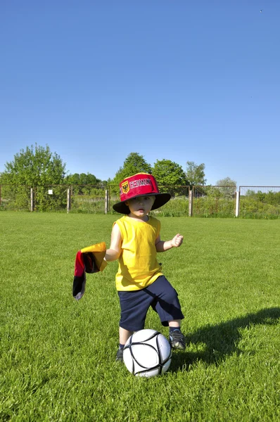 Jeune garçon ou enfant avec drapeau allemand et casquette joue au football ou footba — Photo