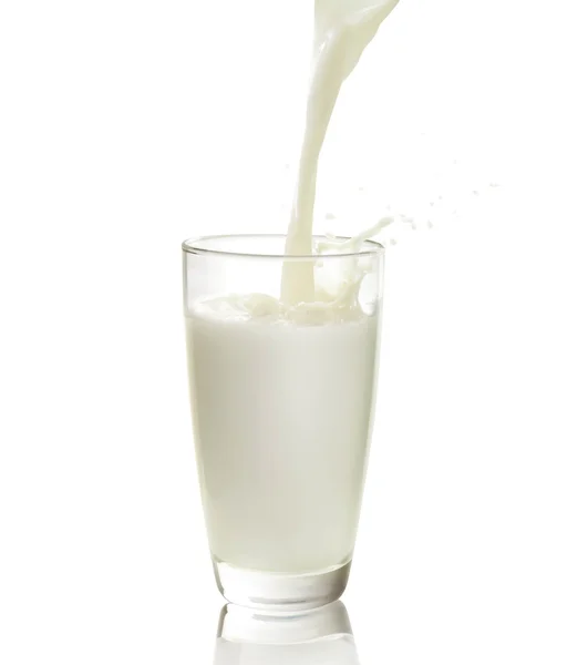 Una jarra de leche y un vaso de leche en una mesa de madera sobre un fondo  azul.