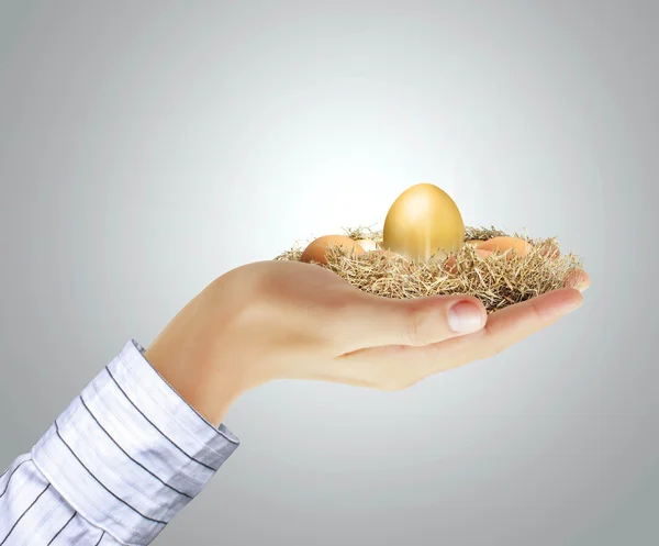 Золотое яйцо в руке — стоковое фото