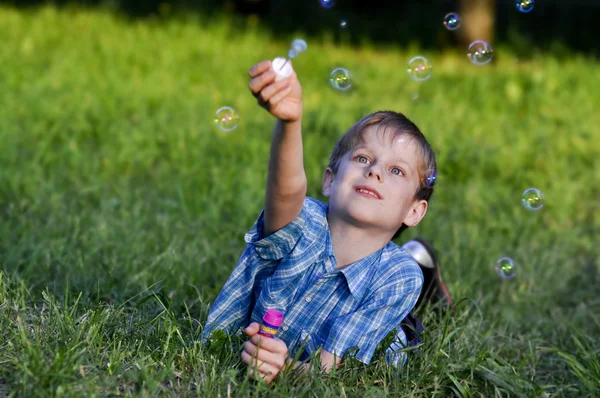 Gelukkige jongen voorsprong opwaarts zeepbellen — Stockfoto