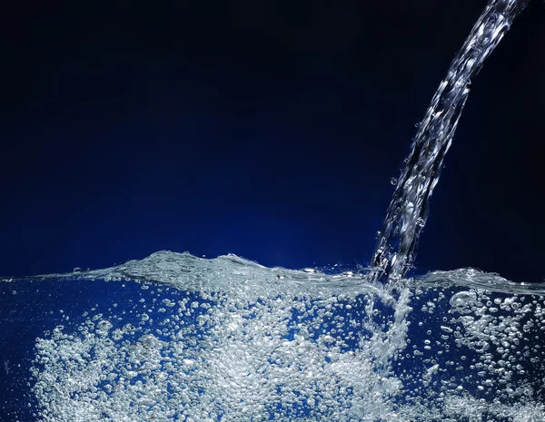 Ρίχνει νερό. Εικόνα παφλασμών σε μπλε φόντο — Φωτογραφία Αρχείου