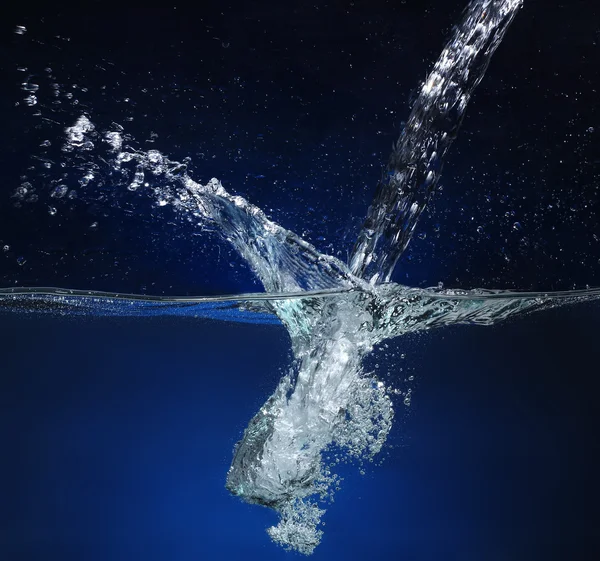 Ρίχνει νερό. Εικόνα παφλασμών σε μπλε φόντο — Φωτογραφία Αρχείου
