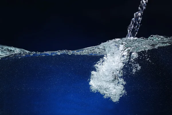 A deitar água. Imagem de respingo em um fundo azul — Fotografia de Stock