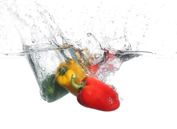 Tre peperoni che cadono in acqua, su fondo bianco — Foto Stock