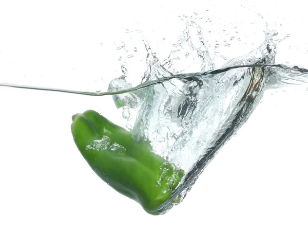 Pimenta verde caindo na água sobre fundo branco — Fotografia de Stock