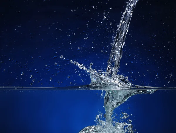 Su dökme. mavi bir arka plan üzerinde sıçrama görüntü — Stok fotoğraf