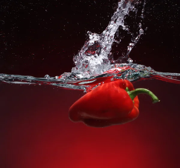 Pepe rosso che cade in acqua. Sfondo con lo stesso tono — Foto Stock