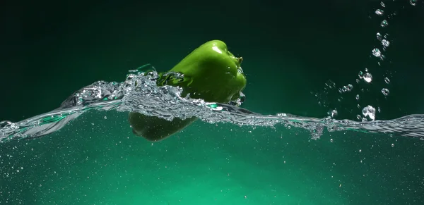 青椒落入水中。绿色背景 — 图库照片