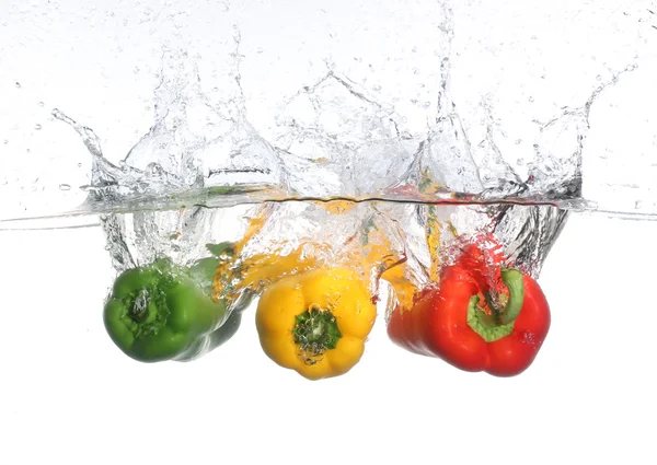 Three peppers falling into water, over white background — Stock Photo, Image
