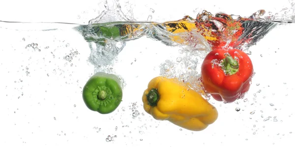 Drie pepers omvallen in water, witte achtergrond — Stockfoto