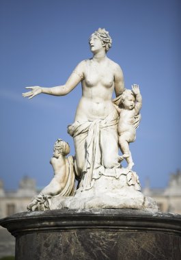 Sculpture of a mother and childs in garden the Royal Palace of Versailles, France