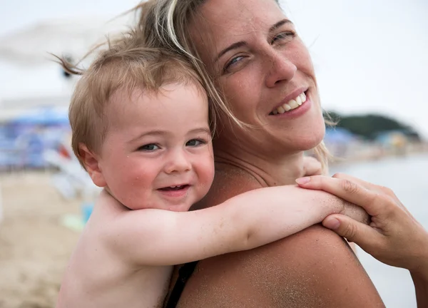 Schöne Mutter und ihr Sohn spielen zusammen am Strand — Stockfoto