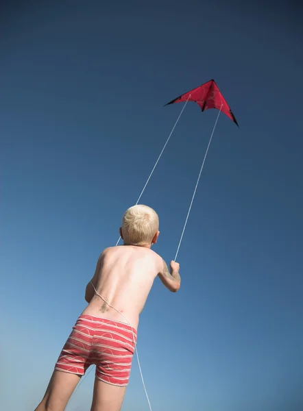 Νεαρό ξανθιά αγόρι παίζει με κόκκινο kite — Φωτογραφία Αρχείου