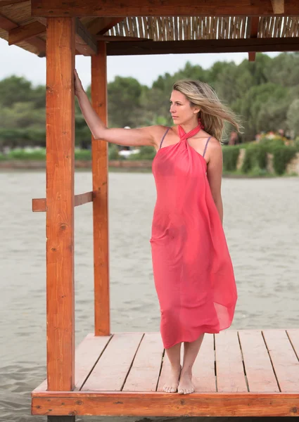 Mooie vrouw in roze, staan op het strand — Stockfoto
