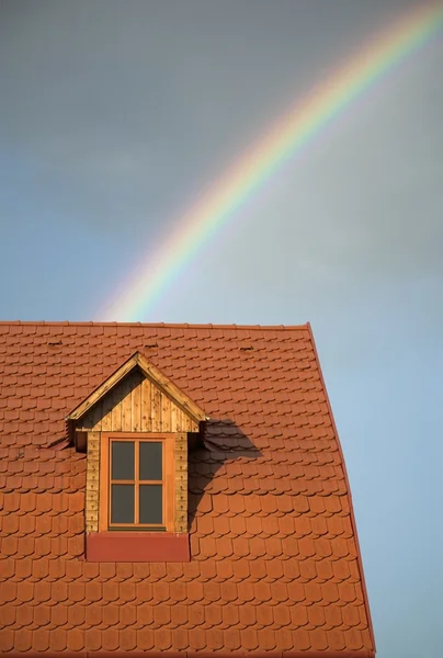 Rainbow beyond a reddish roof of a house — Stock Photo, Image