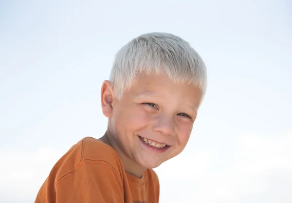 Rapazinho alegre, camisa laranja, céu azul — Fotografia de Stock