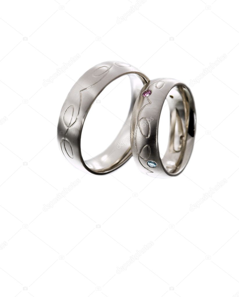 A pair of wedding rings set with colorful diamonds on white background