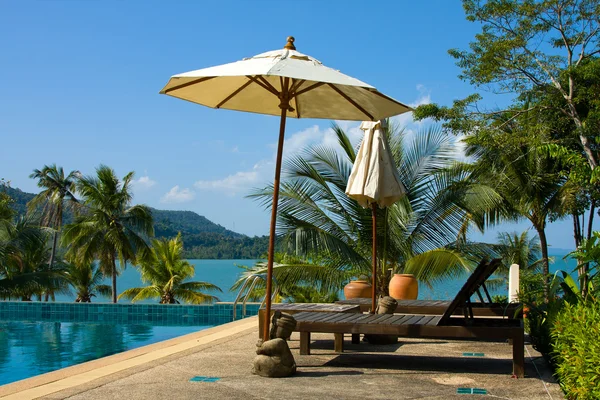 Blue swimming pool water and palm trees near the sea — Stock Photo, Image