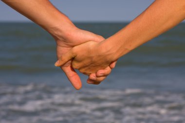 Couple of hands against the sea view clipart