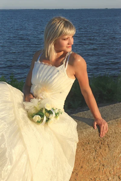 Невеста на фоне моря со свадебным букетом — стоковое фото