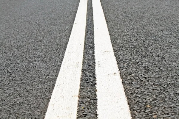 Due linee bianche su una strada asfaltata — Foto Stock