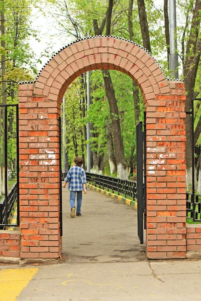 stock image The red brick gate and a going out boy