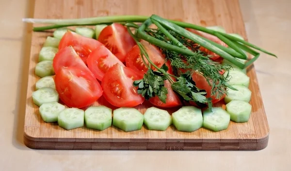 Свежие нарезанные овощи и зелень на доске — стоковое фото