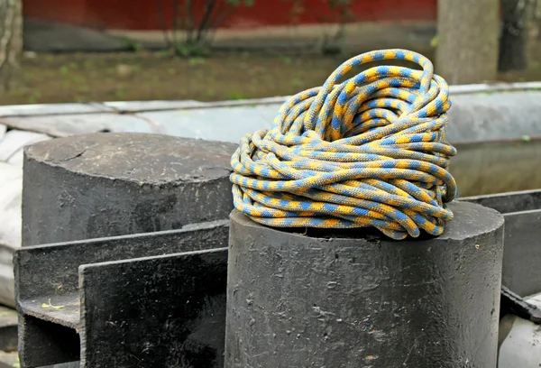 Montaggio: corda arrotolata blu e gialla sul tubo — Foto Stock