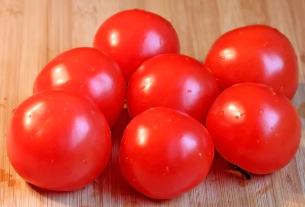 Сырые помидоры на деревянной доске — стоковое фото