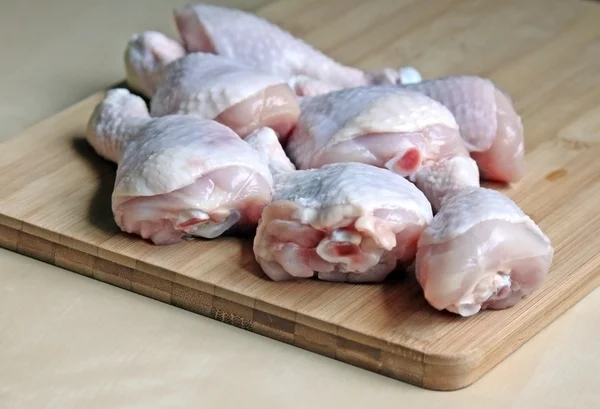 Raw chicken legs on a wooden chopping board — Stock Photo, Image