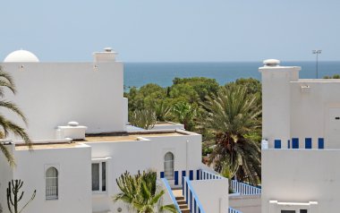 Beautiful view of sea, horizon, palms and white buildings clipart