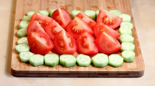 Nyklippt gurkor och tomater på en trä skärbräda — Stockfoto