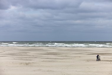 Landscape of a beach with man pushing his bike clipart