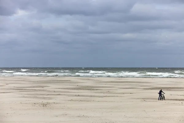 Pejzaż plaża z mężczyzna popychając jego rower — Zdjęcie stockowe