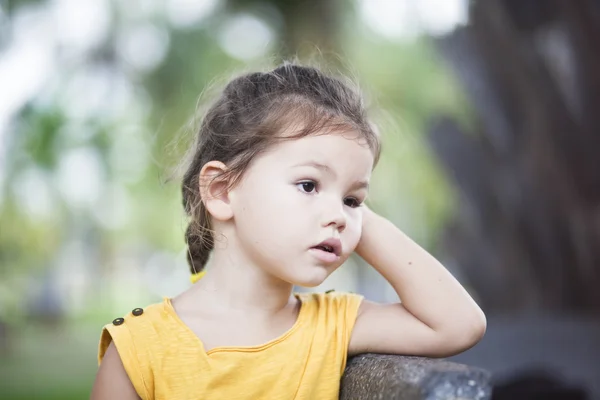 Het kleine meisje zit op een bankje op vakantie — Stockfoto