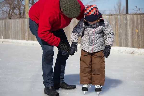 Padre enseñando a hijo a patinar sobre hielo — Foto de Stock