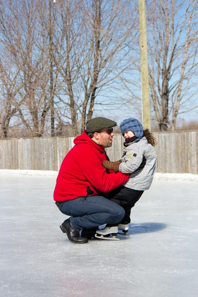 Padre enseñando a su hija a patinar sobre hielo — Foto de Stock