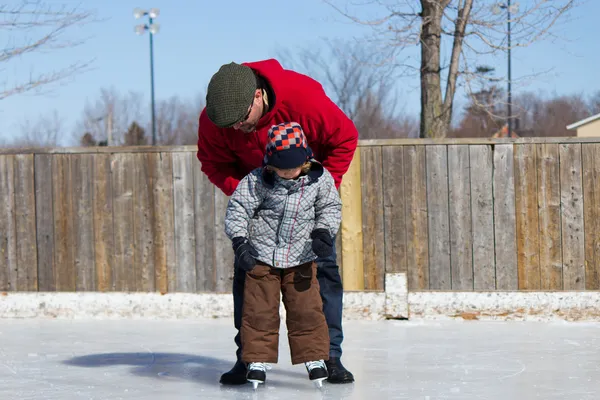 Father teaching son how to ice skate — Stok fotoğraf